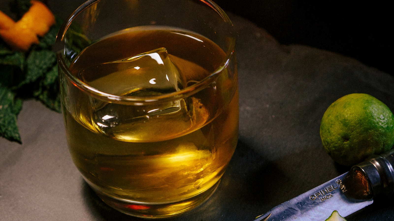 Clear ice cube made by the OnTheRocks Ice Box floating in whiskey