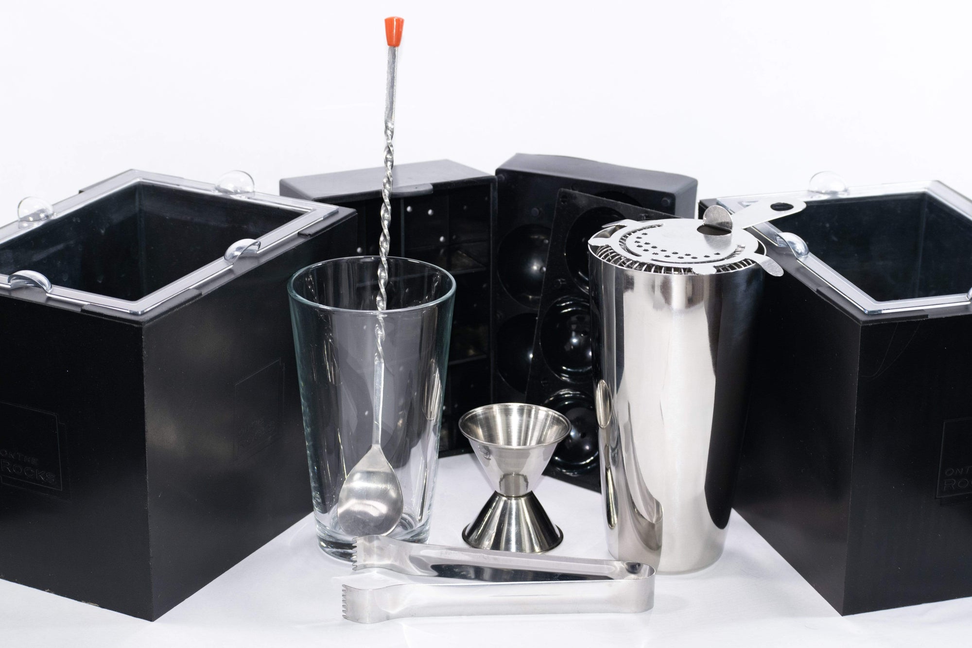 Minimalist cocktail kit featuring strainer, cocktail spoon, jigger, shaker, and ice tongs plus two OnTheRocks IceBoxes that make large clear ice cubes and spheres easily at home