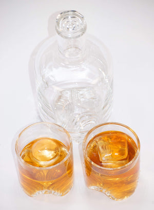 Handblown glass decanter with unique three leg layered base made by Pittsburgh glass artist John Sharvin pictured with two handblown glass tumblers including OnTheRocks clear ice cubes and spheres (not included with this product)